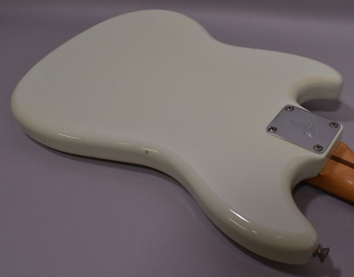 The back of a light blue bass body with a chrome neck plate and a small chip near the lower horn.