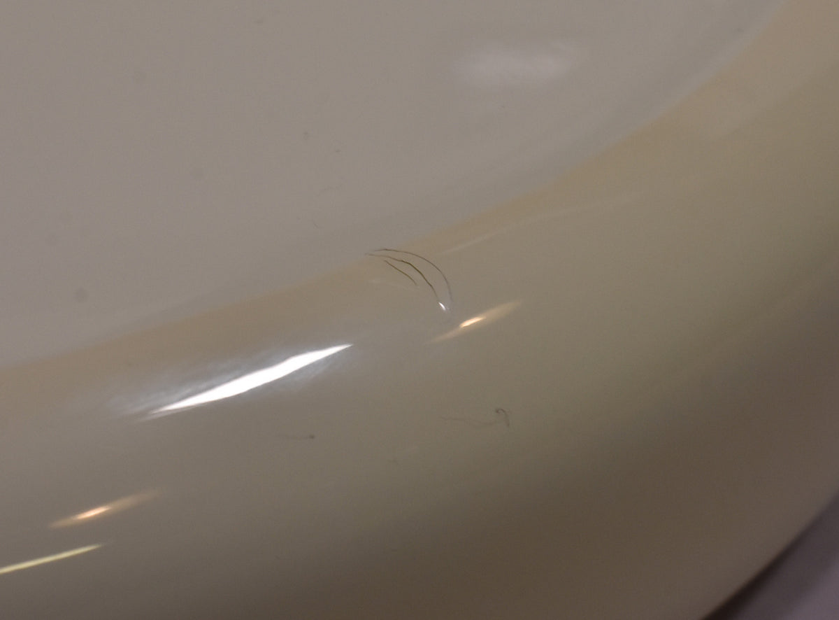 Close-up of the Sonic Blue bass body, showing a few small, dark scratches on the glossy finish.