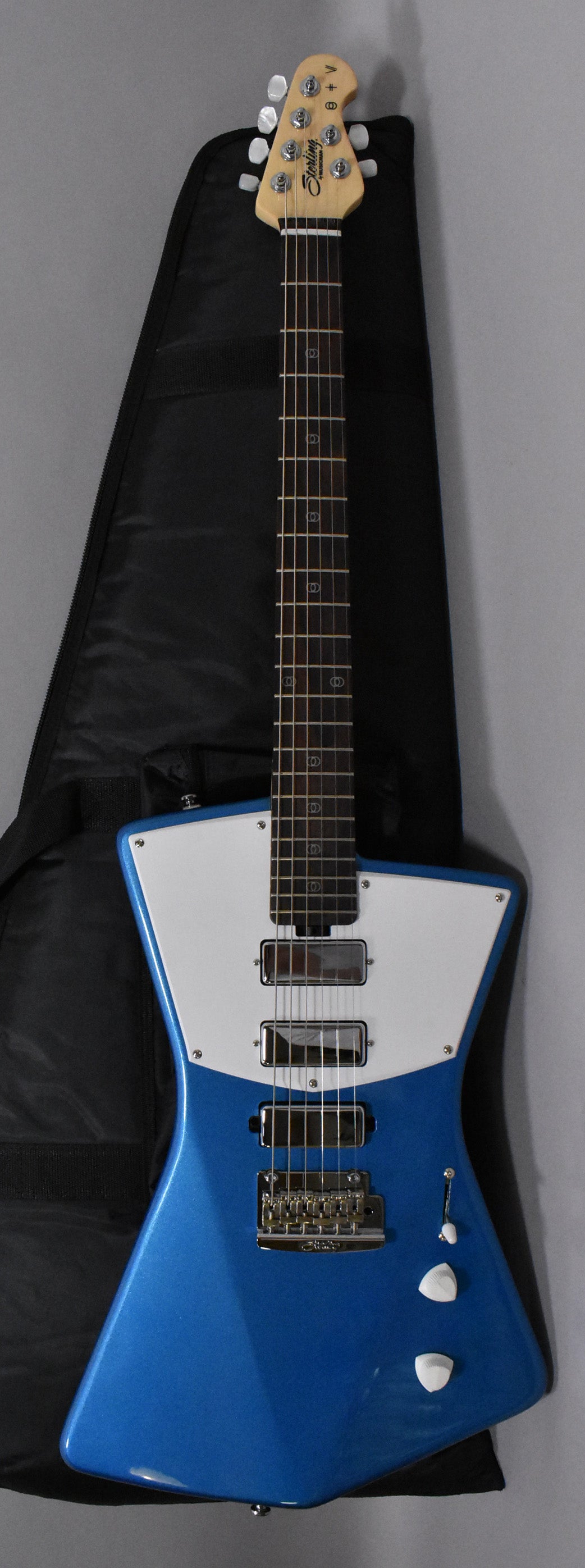 Full view of a blue and white electric guitar with a black gig bag behind it.