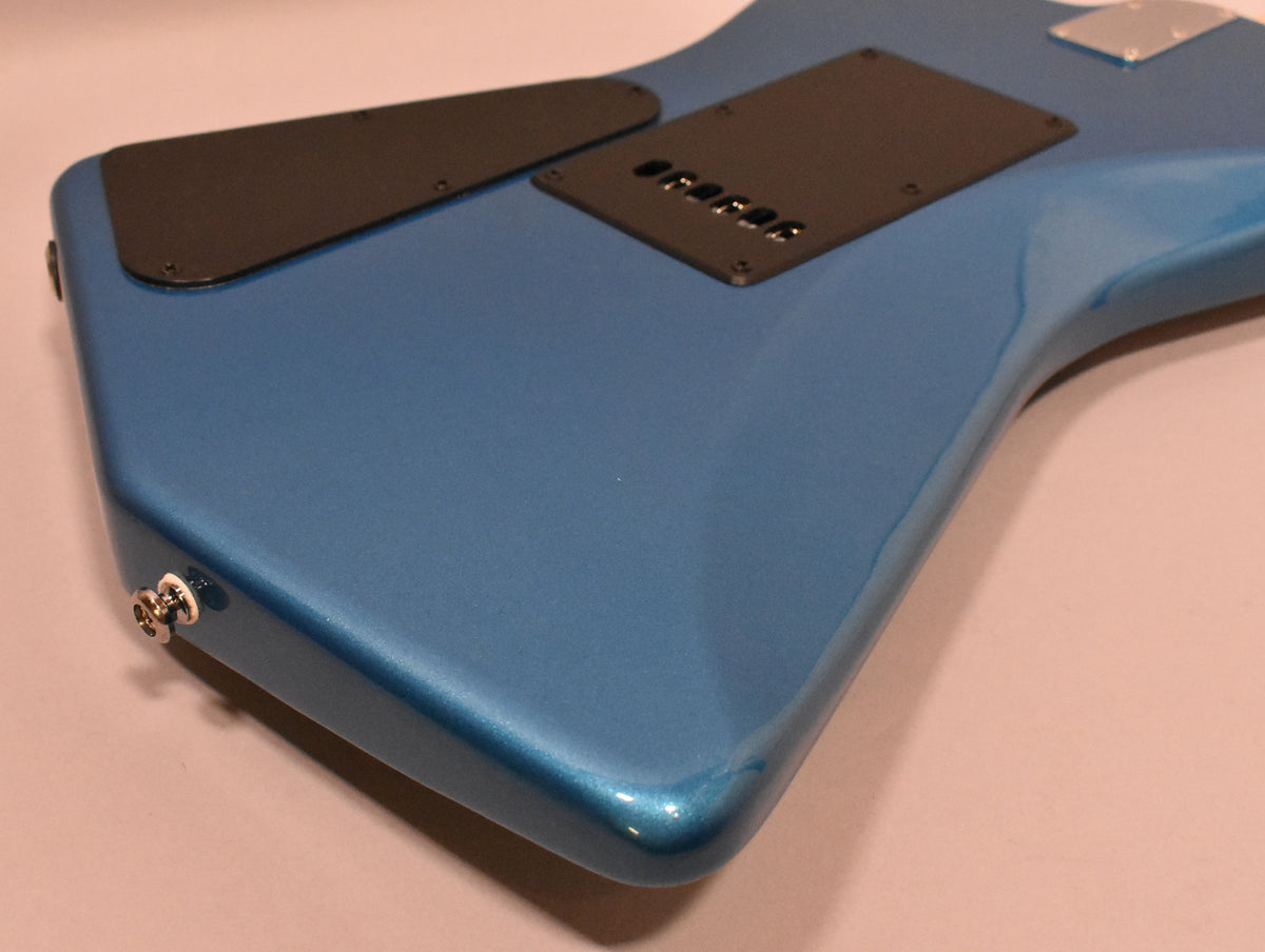 The back of a metallic blue guitar body, angled from the lower bout, showing two black control plates and a chrome output jack.
