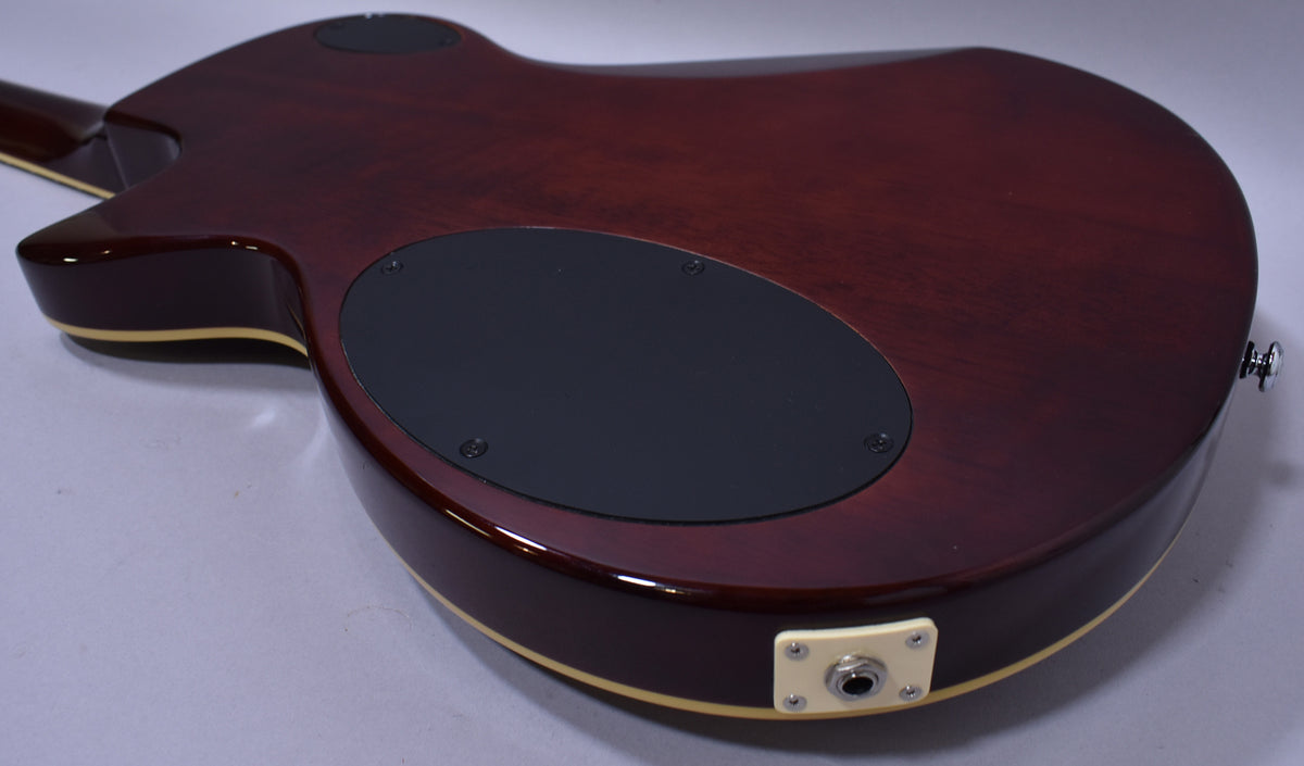 The guitar's dark sunburst back, with a large black control plate and cream output jack, shows light surface wear.