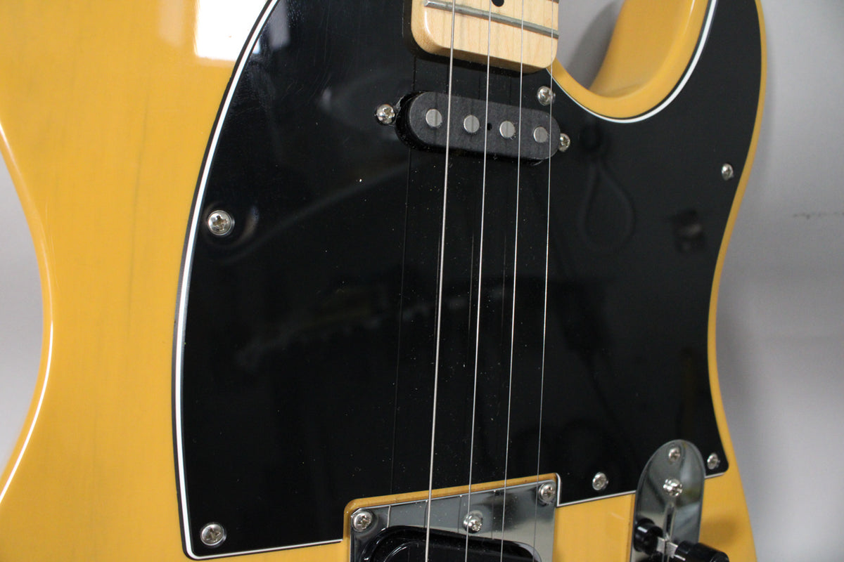 Close-up of the glossy butterscotch body and black pickguard, showing the neck pickup, strings, and chrome bridge pickup surround.