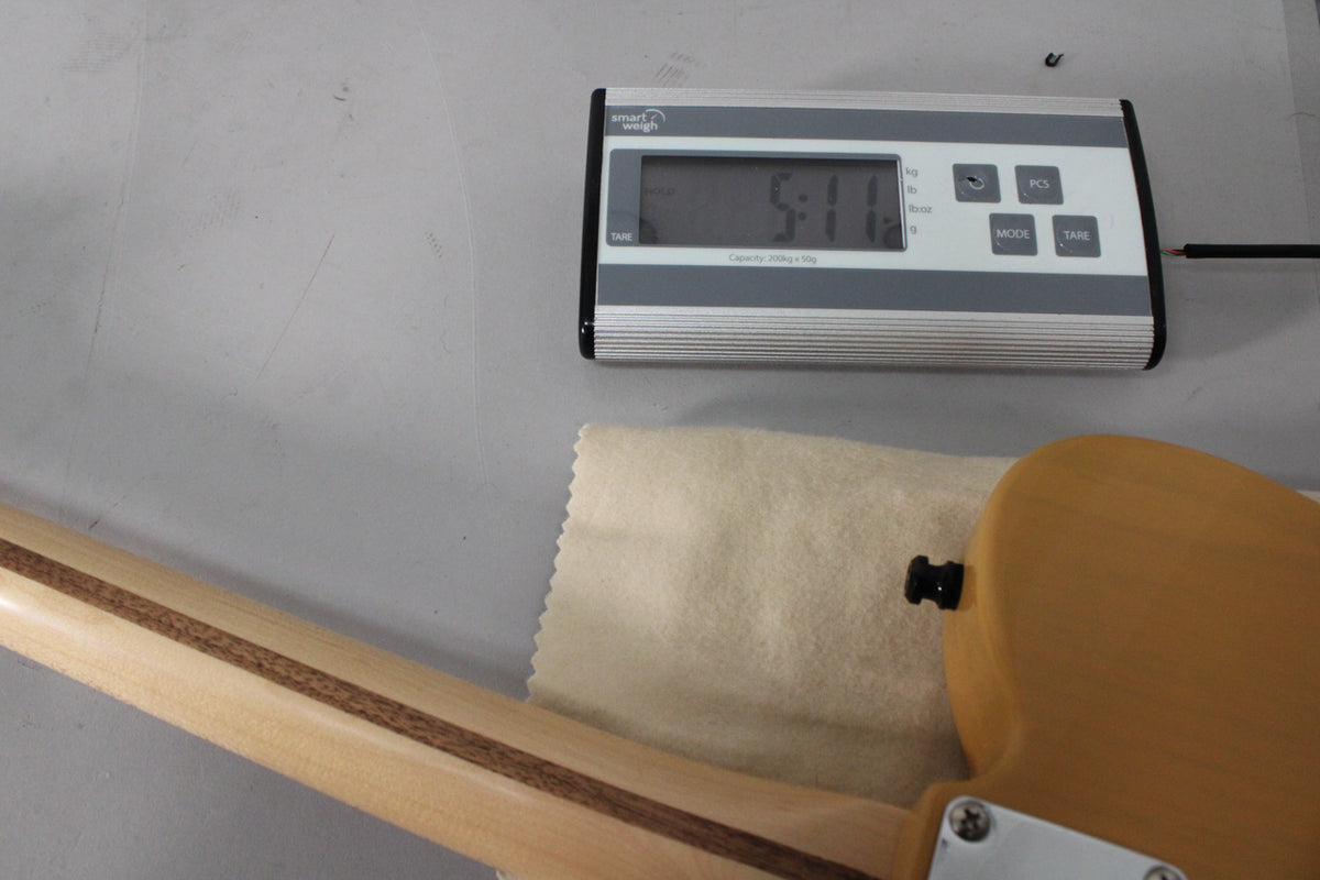 The guitar's neck and part of its butterscotch body are shown, with a digital scale displaying "5:11" in the background.