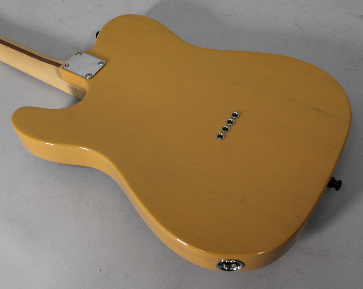 The back of a butterscotch blonde Telecaster body, showing the neck plate, string ferrules, and output jack.