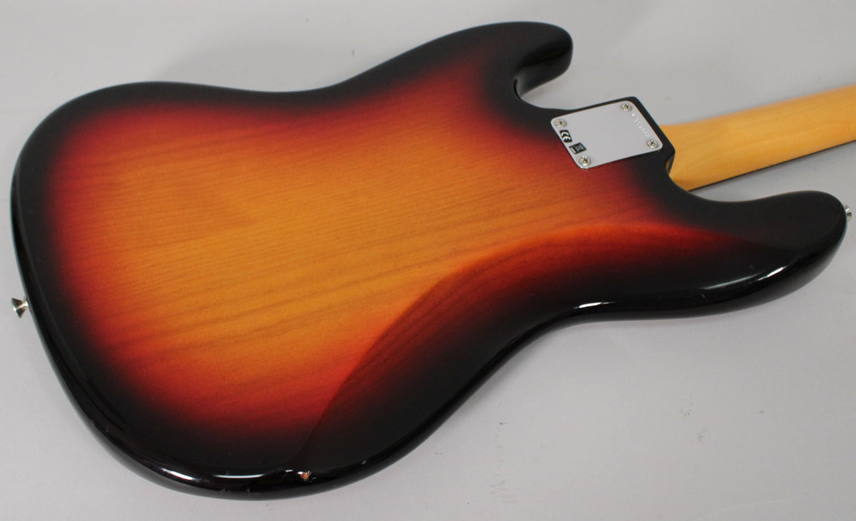 The back of a glossy 3-color sunburst bass body, angled from the lower left, with a chrome neck plate and a small chip on the lower edge.