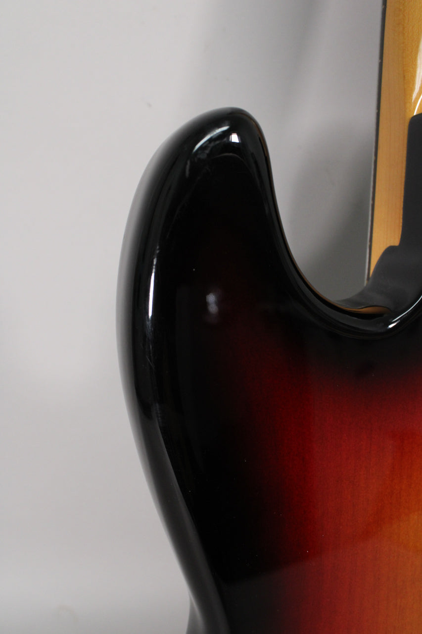 Close-up of the upper horn and cutaway of the sunburst bass, showing the glossy black finish blending into dark red and orange.