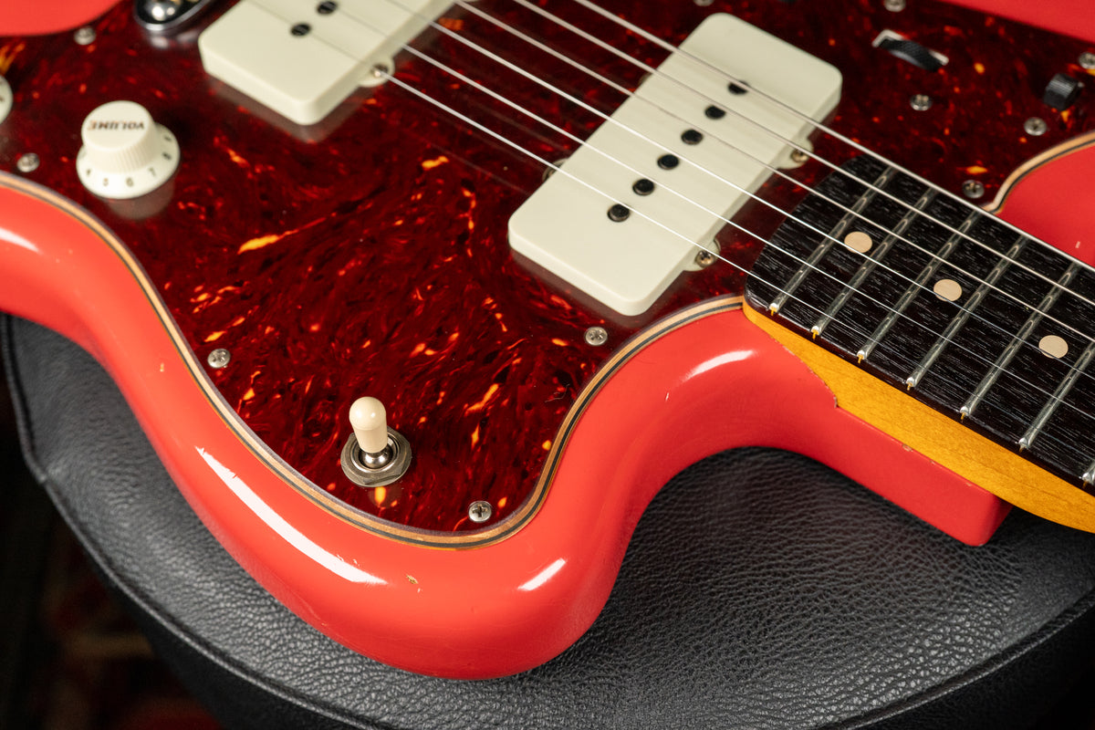 Close-up of the Fiesta Red Jazzmaster body, showing the tortoiseshell pickguard, white pickups, volume knob, and toggle switch.
