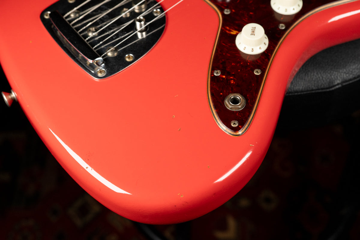 Close-up of the Fiesta Red body, showing the vibrato, tortoiseshell pickguard, white control knobs, output jack, and light relic wear.