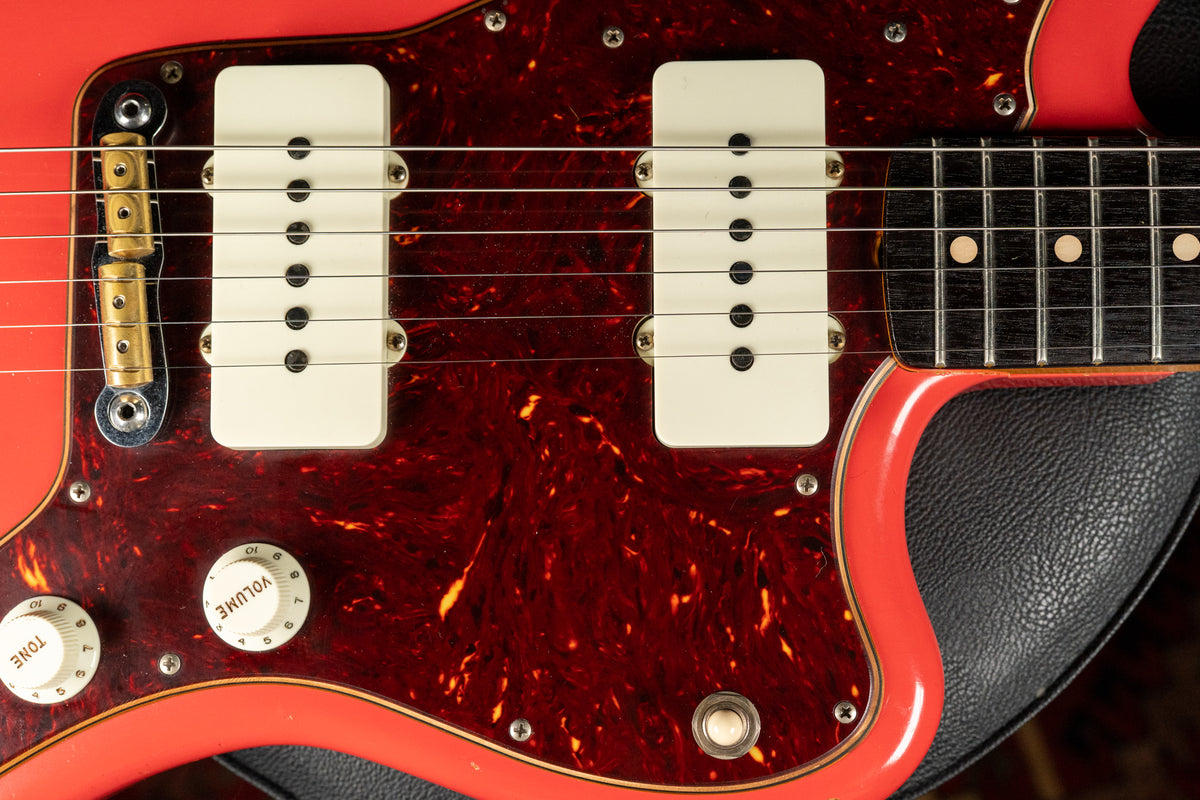 Close-up of a Fiesta Red guitar body with a tortoiseshell pickguard, two cream P90 pickups, and aged white volume/tone knobs.