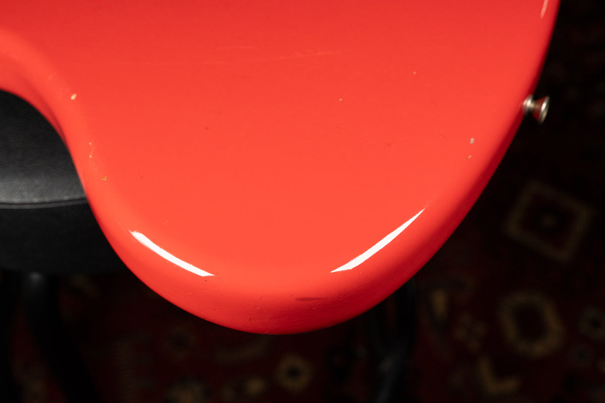 Close-up of the guitar's lower bout in Fiesta Red, showing a few small white relic'd chips and the chrome strap button on the upper right.