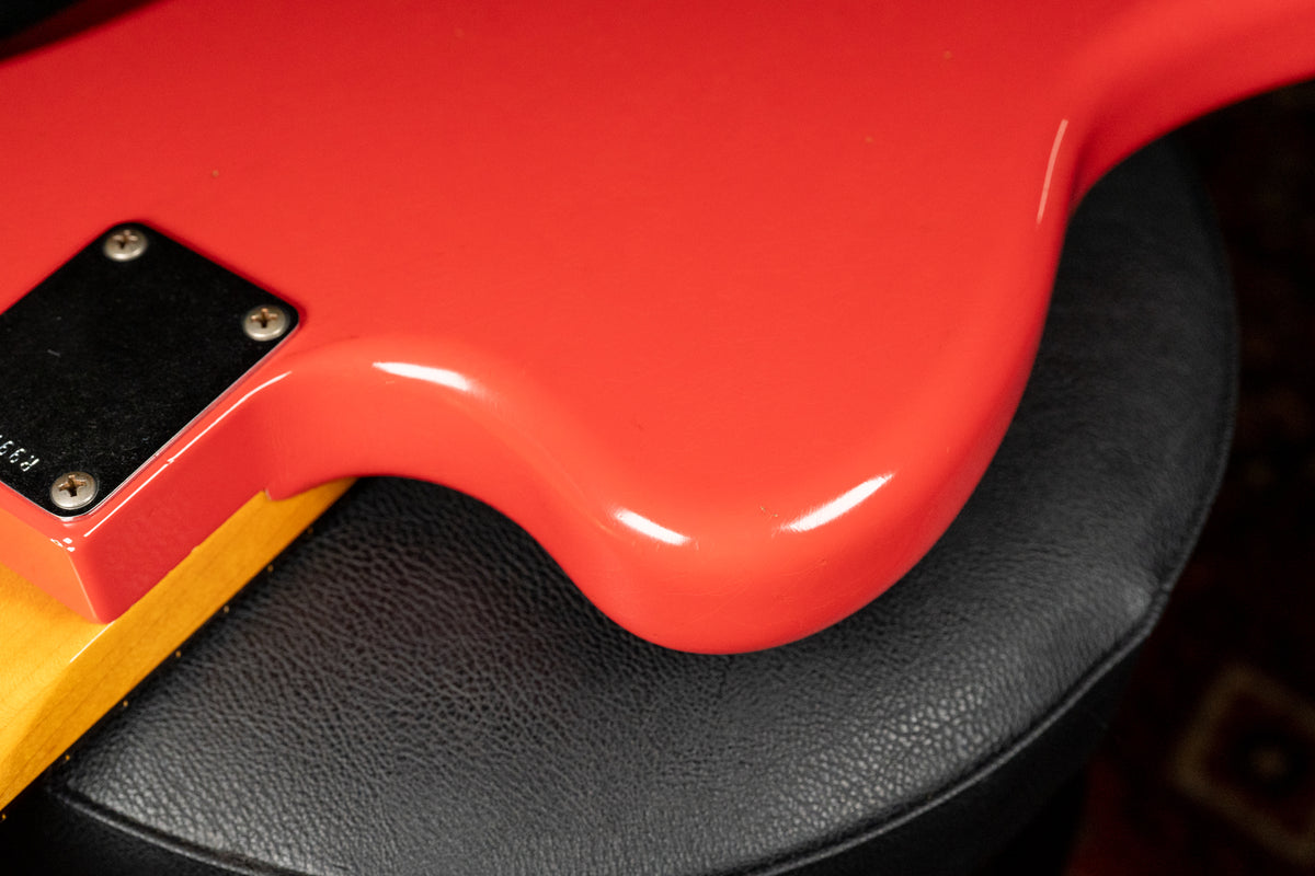 Close-up of the Fiesta Red guitar body's lower bout and neck heel, showing the glossy finish and light relic wear.