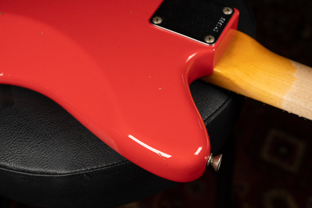 Close-up of the guitar's lower bout in Fiesta Red, showing a strap button, neck plate, and the worn, ambered maple neck heel.