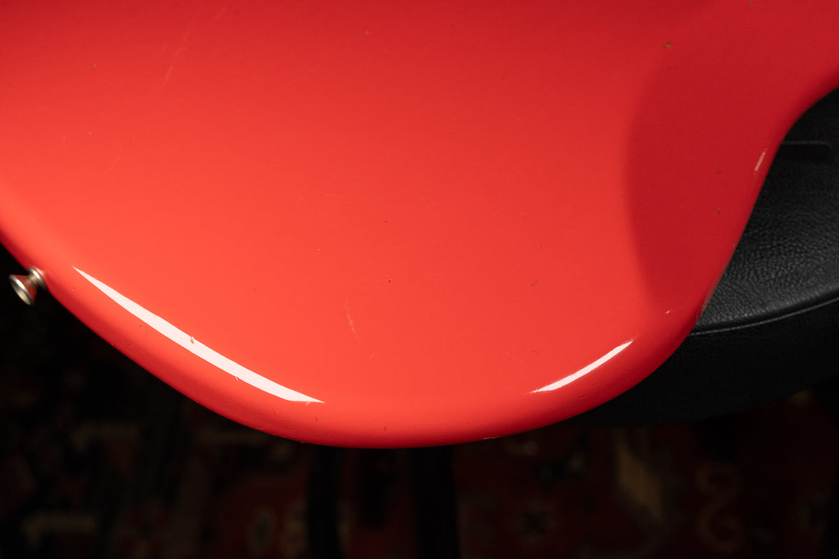Close-up of the Fiesta Red body's lower bout, revealing light surface scratches and a strap button on the curved edge.
