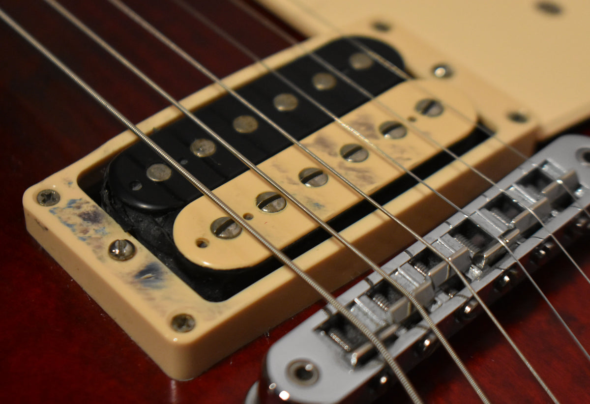 Close-up of the bridge pickup, showing its cream and black bobbins, surrounded by a worn cream pickup ring.