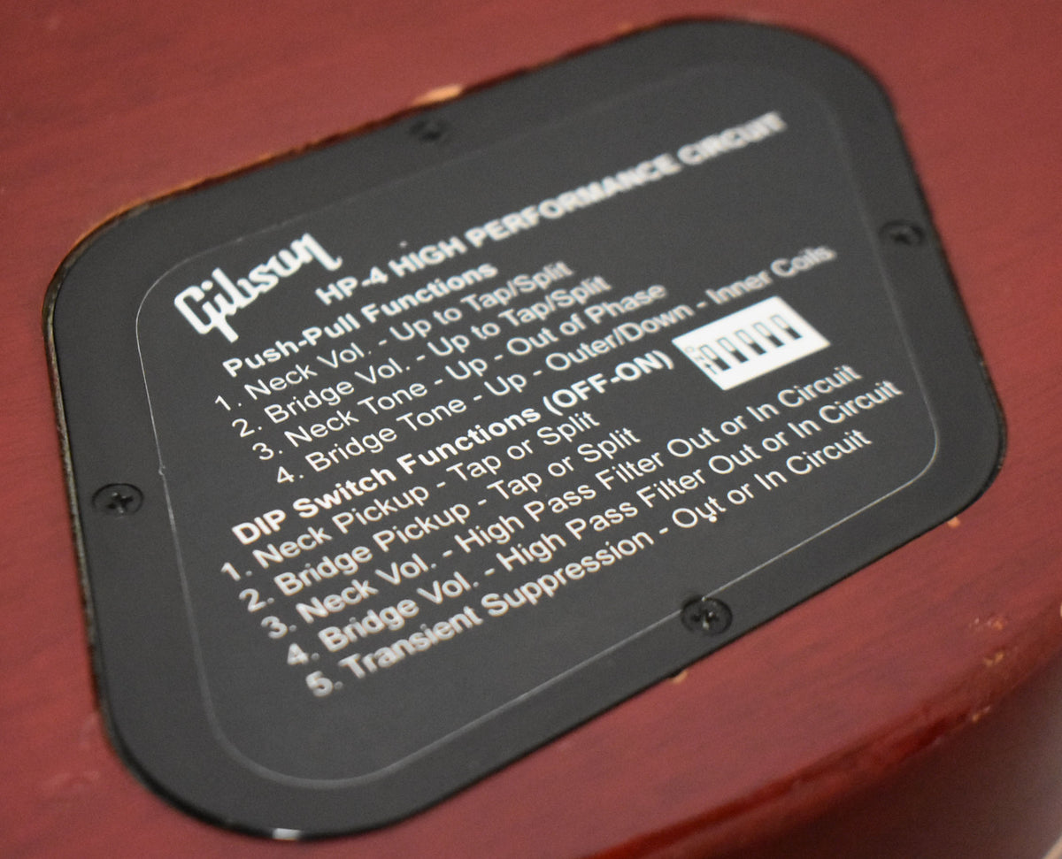 Close-up of the guitar's wine red body, showing the black control cavity cover with white text detailing the HP-4 High Performance Circuit.
