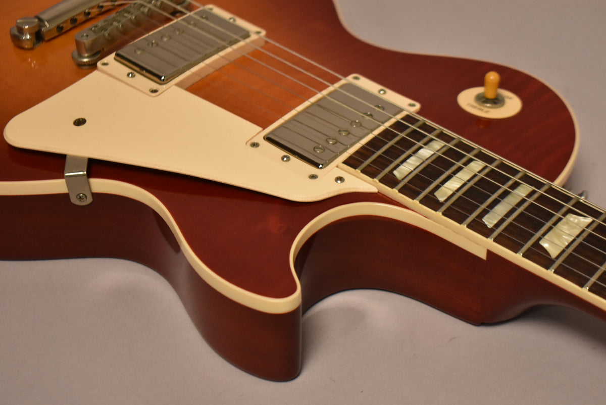 Close-up of the cherry sunburst body, showing the cream pickguard, two humbuckers, and the fretboard with trapezoid inlays.