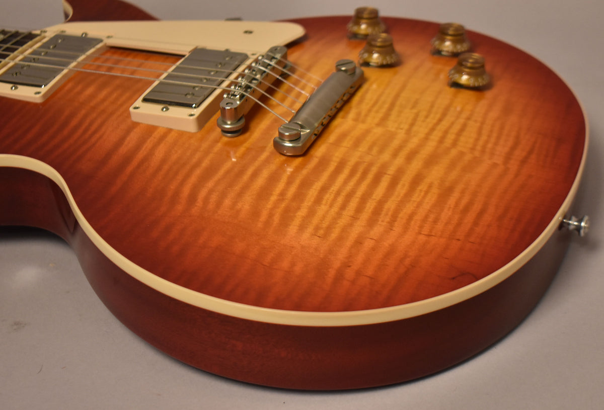 The Les Paul's Heritage Cherry Sunburst top shows prominent flame maple grain, with cream binding, nickel hardware, and amber top hat knobs.