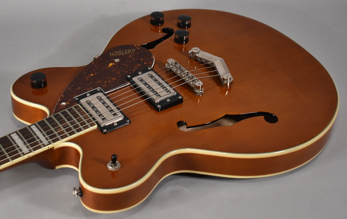 Close-up of a glossy sunburst semi-hollowbody guitar, showing the upper bout, f-holes, two humbuckers, and a tortoiseshell pickguard.