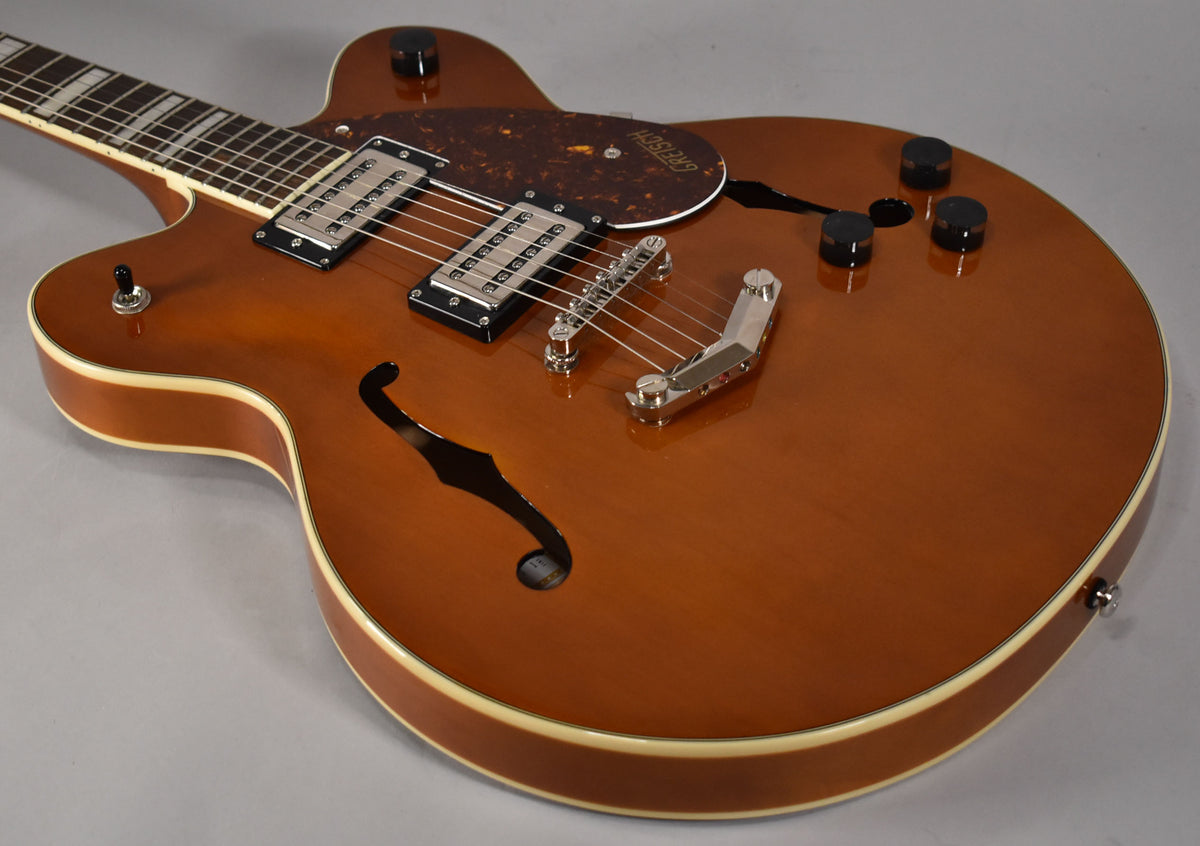 A sunburst semi-hollowbody electric guitar, angled from the neck, showing the f-hole, two humbuckers, and a chrome Bigsby-style tremolo.