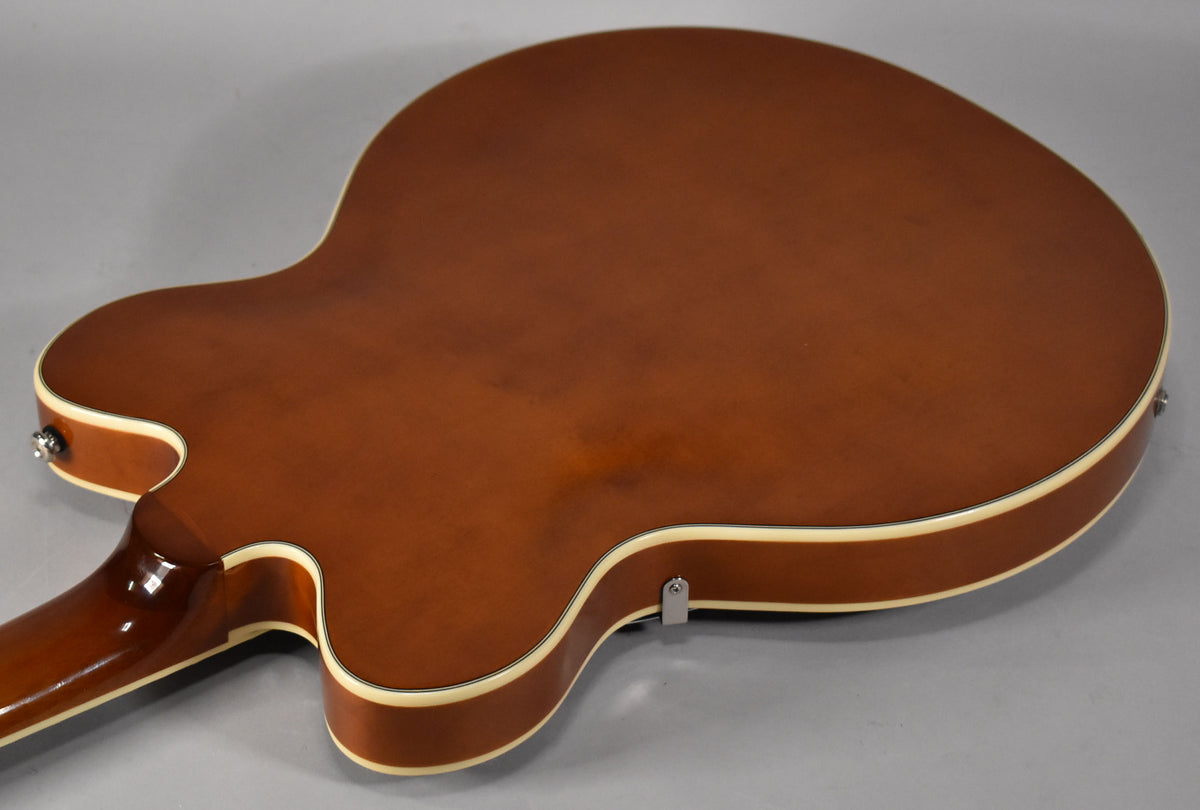 The guitar's sunburst back and sides are visible, with cream binding and two chrome strap buttons.