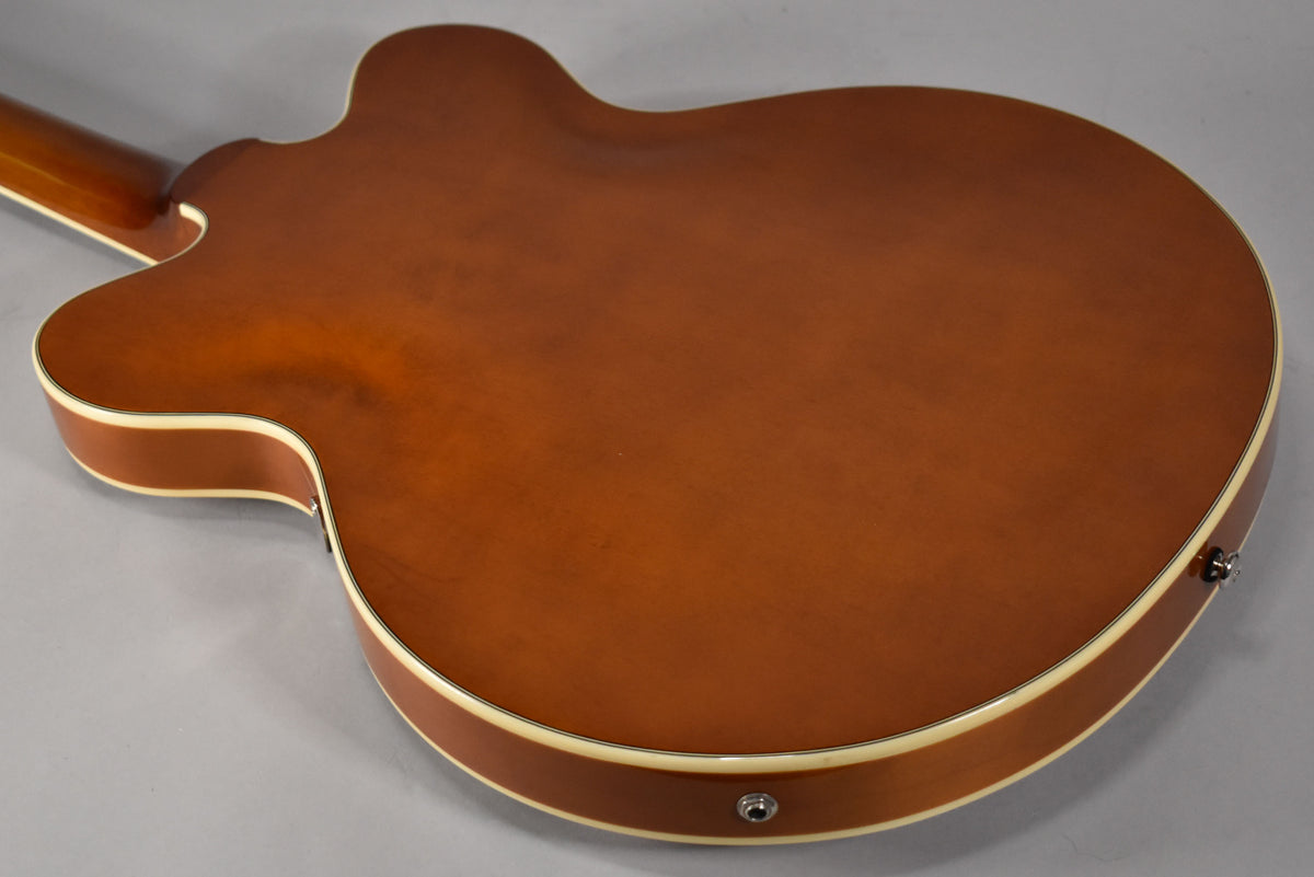 The back of a semi-hollowbody electric guitar, showing its sunburst finish, cream binding, and two strap buttons.