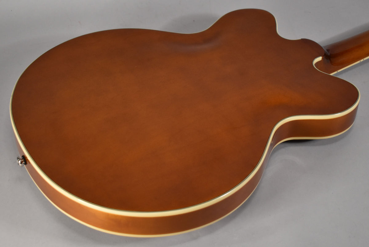 The back of a sunburst semi-hollowbody guitar, showing the brown body with cream binding and a small portion of the neck.