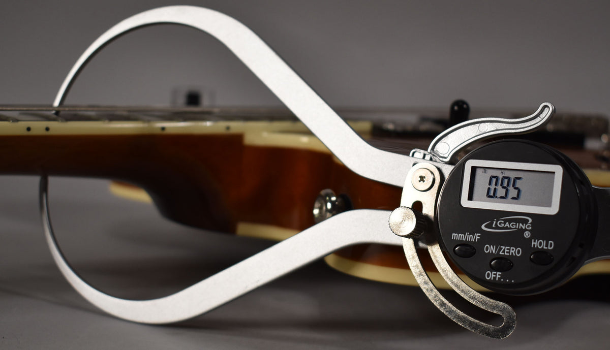 A digital caliper measures the neck relief of the sunburst semi-hollowbody guitar, showing 0.95mm.