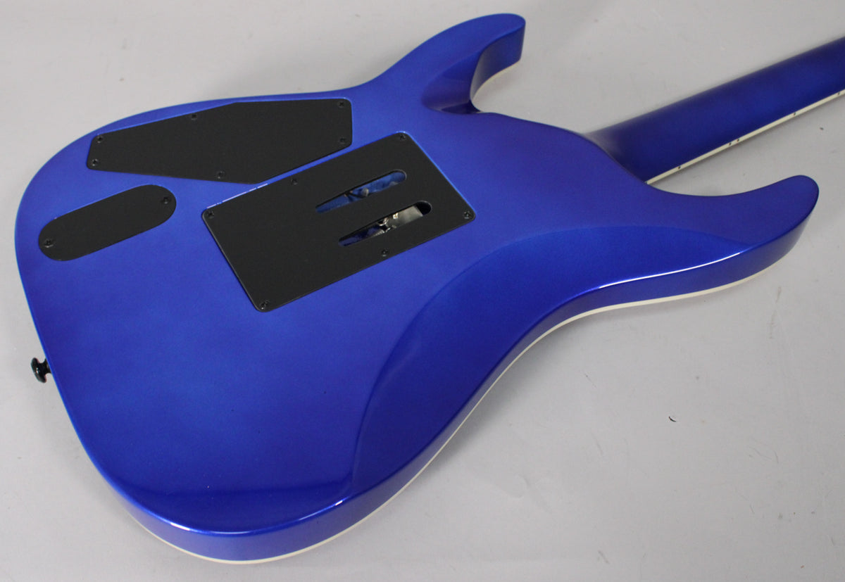 The back of a metallic blue electric guitar, showing control cavity covers and the tremolo spring cavity, with a white binding.