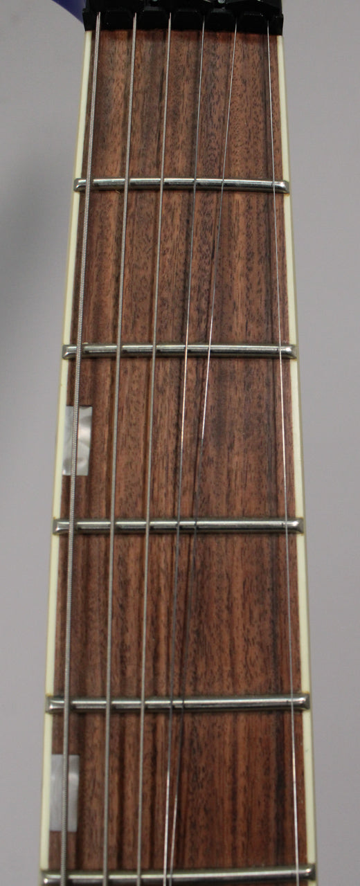 Close-up of the guitar's dark brown fretboard with six strings, metal frets, and rectangular mother-of-pearl inlays.