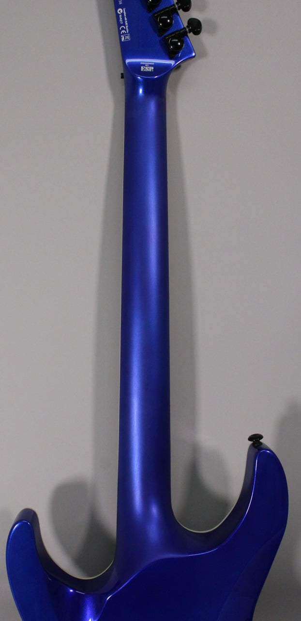 The back of a blue metallic electric guitar, showing the neck and upper body with a strap button and black tuners.