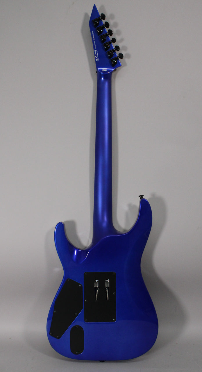The back of a blue metallic electric guitar is shown, with a black control cavity cover and a tremolo spring cover.