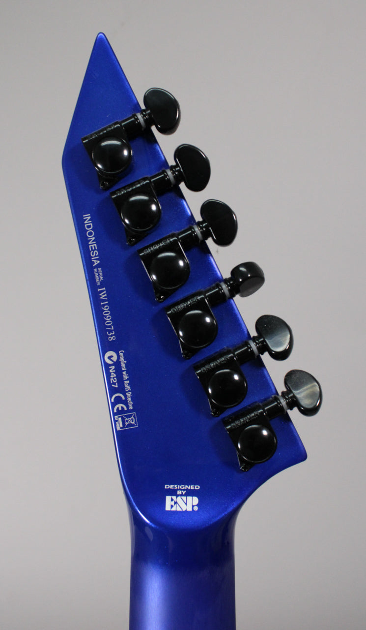 Angled view of the guitar's blue pearl fade metallic headstock, showing six black Grover tuners and the neck joint.