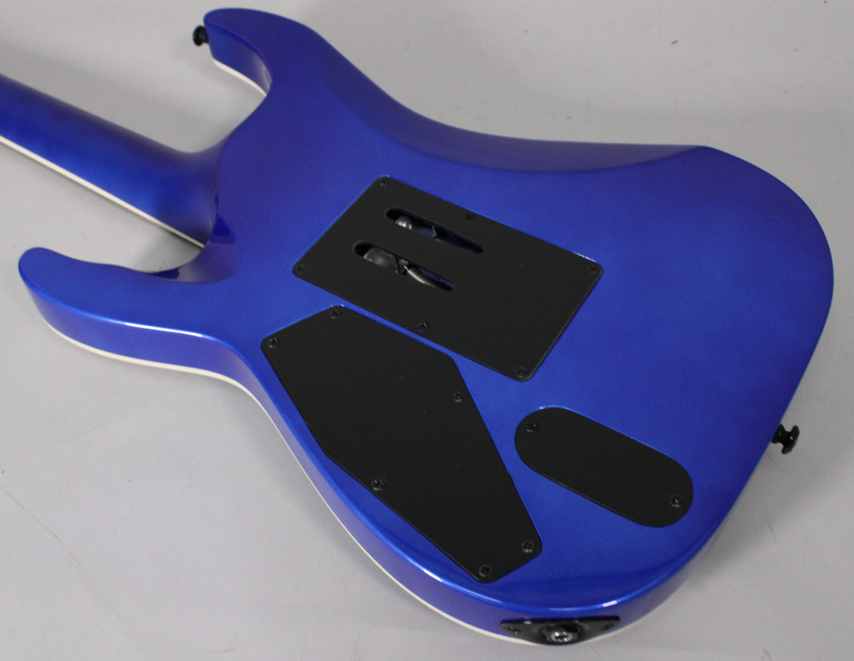 Rear view of a metallic blue electric guitar body with three black control cavity covers and a white binding.