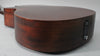 The lower bout of the dark brown acoustic guitar, showing the satin finish, endpin jack, and a small ding on the top edge.
