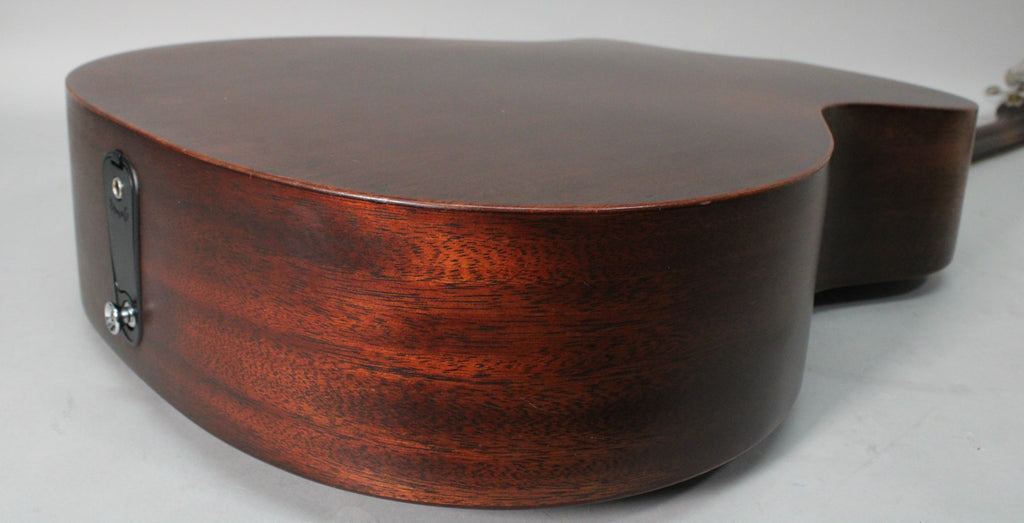 The guitar's dark brown body, with visible wood grain, is viewed from the lower bout, showing the black endpin jack.