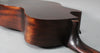 The dark brown acoustic guitar body and neck join, showing the cutaway and a strap button.