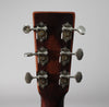 The back of the guitar's dark brown headstock, showing six open-gear tuners with silver plates and brass gears.