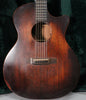 Full front view of the dark reddish-brown acoustic guitar, showing the body, soundhole, bridge, and lower fretboard.