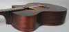 The dark brown acoustic guitar is angled from the lower bout, showing the cutaway, soundhole, bridge, and fretboard.