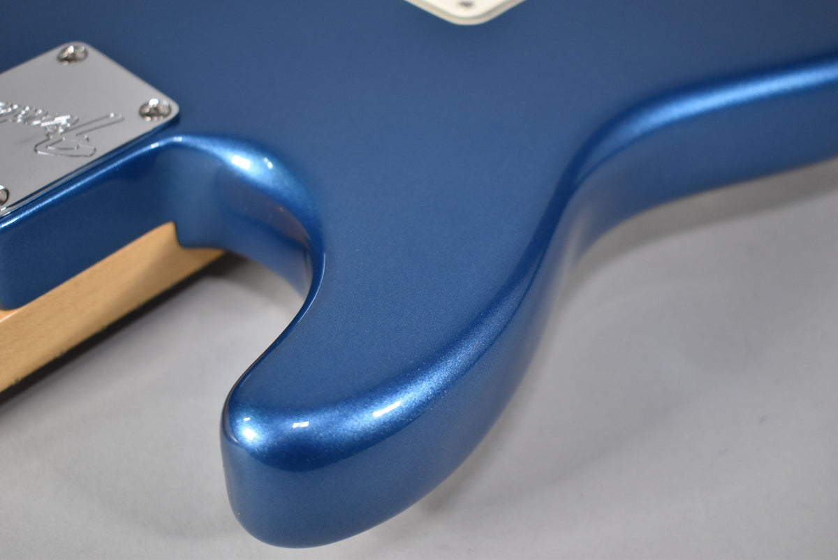 Close-up of the Stratocaster's lower horn and neck joint, showing the metallic blue satin finish and chrome neck plate.