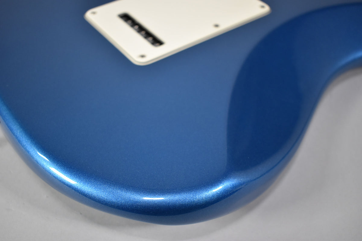 Close-up of the Stratocaster's lower bout, showing the metallic satin Lake Placid Blue finish and a partial view of the white tremolo cover.