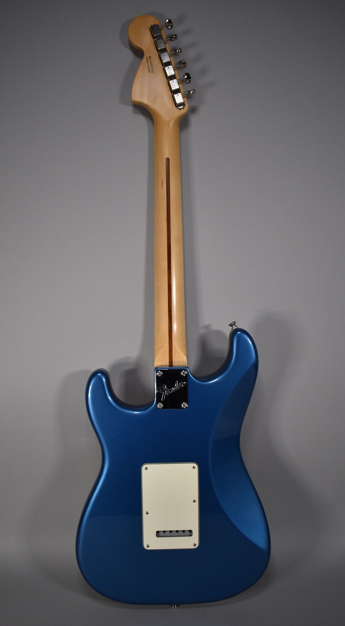 The back of a satin Lake Placid Blue Stratocaster with a maple neck, chrome tuners, and a cream tremolo cover.