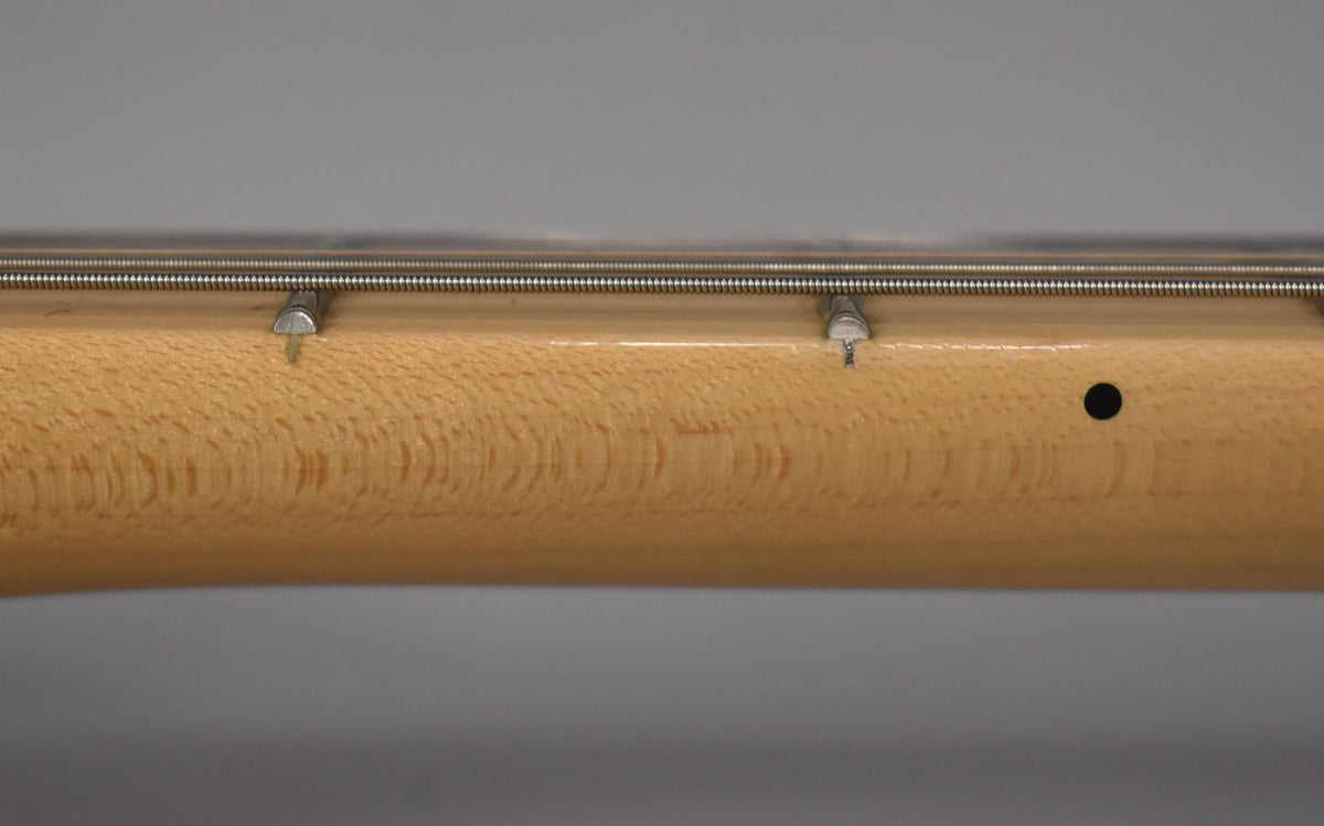 Close-up of the maple neck's side, showing two string trees, a black side dot, and subtle flame figuring in the wood.