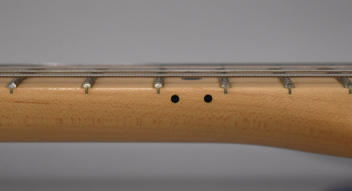 Close-up of the maple fretboard and frets, showing two black dot inlays between the 11th and 12th frets.