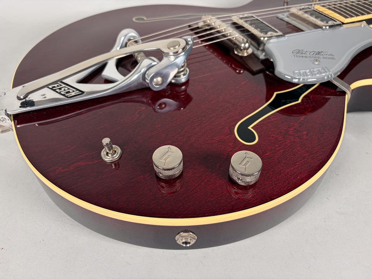 Close-up of the deep red hollow body, showing the Bigsby vibrato, two knurled chrome control knobs, and a toggle switch.