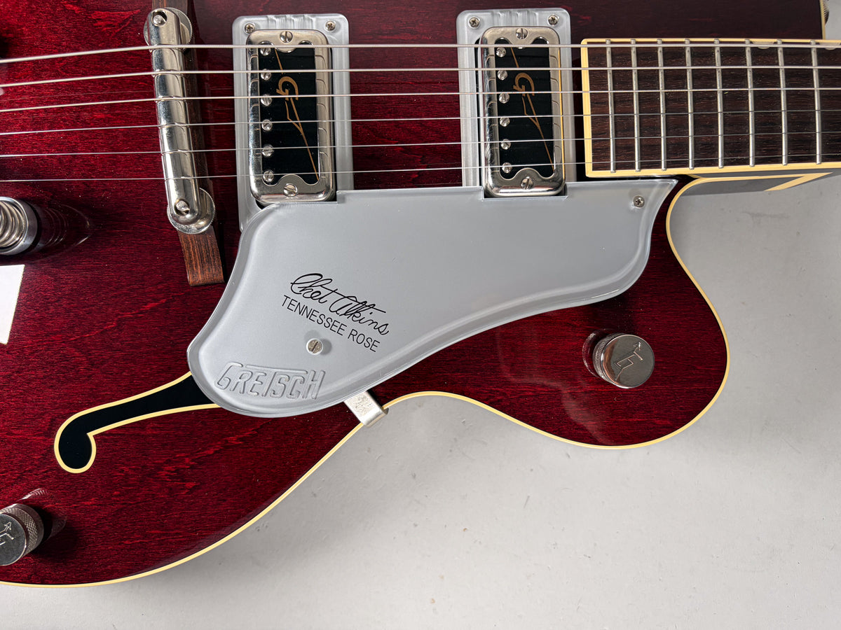 Close-up of the deep red hollow body, showing the bridge pickup, silver pickguard with script, and a chrome control knob.