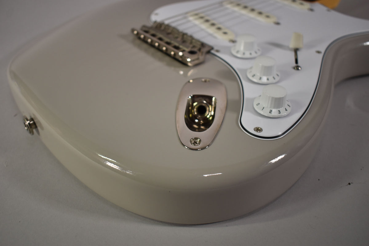 Close-up of the lower bout of a glossy moc sand guitar, showing the input jack, three white numbered control knobs, and a white pickguard.