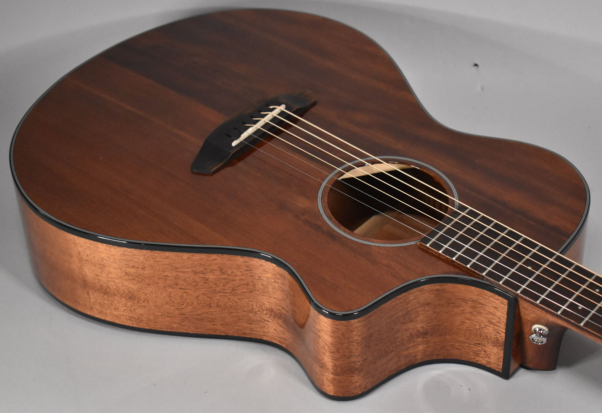 The dark brown acoustic guitar is angled from the upper left, showing the body, soundhole, bridge, and part of the neck.