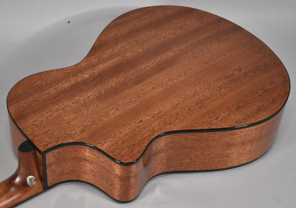 The guitar's back and cutaway are visible, showing a reddish-brown mahogany wood grain with a satin finish and black binding.