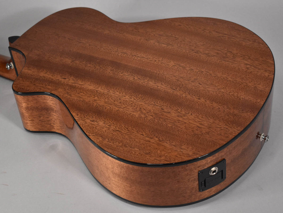 The acoustic guitar's mahogany back and sides are visible, with a black output jack and strap button on the lower bout.